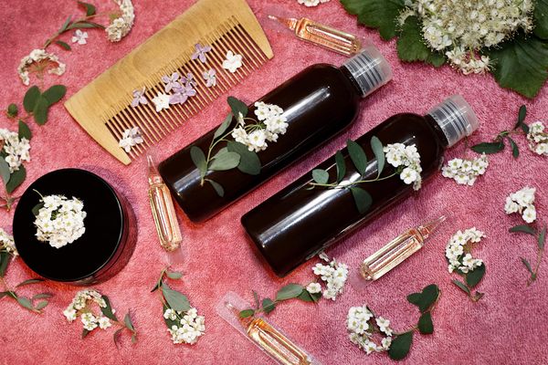 hair care product in fresh flowers on a pink towel.