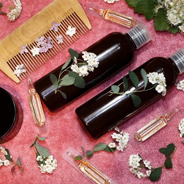 hair care product in fresh flowers on a pink towel.
