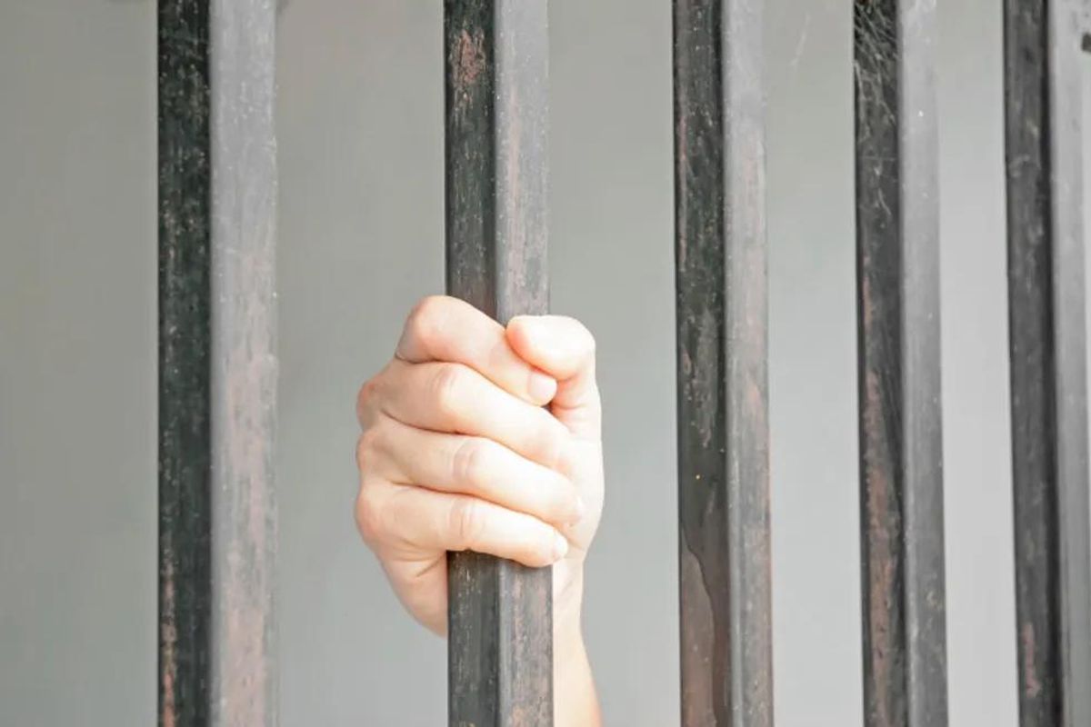 hands of woman behind bars