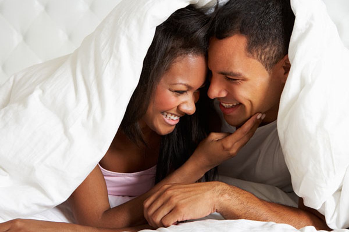 happy couple laying in bed under the covers