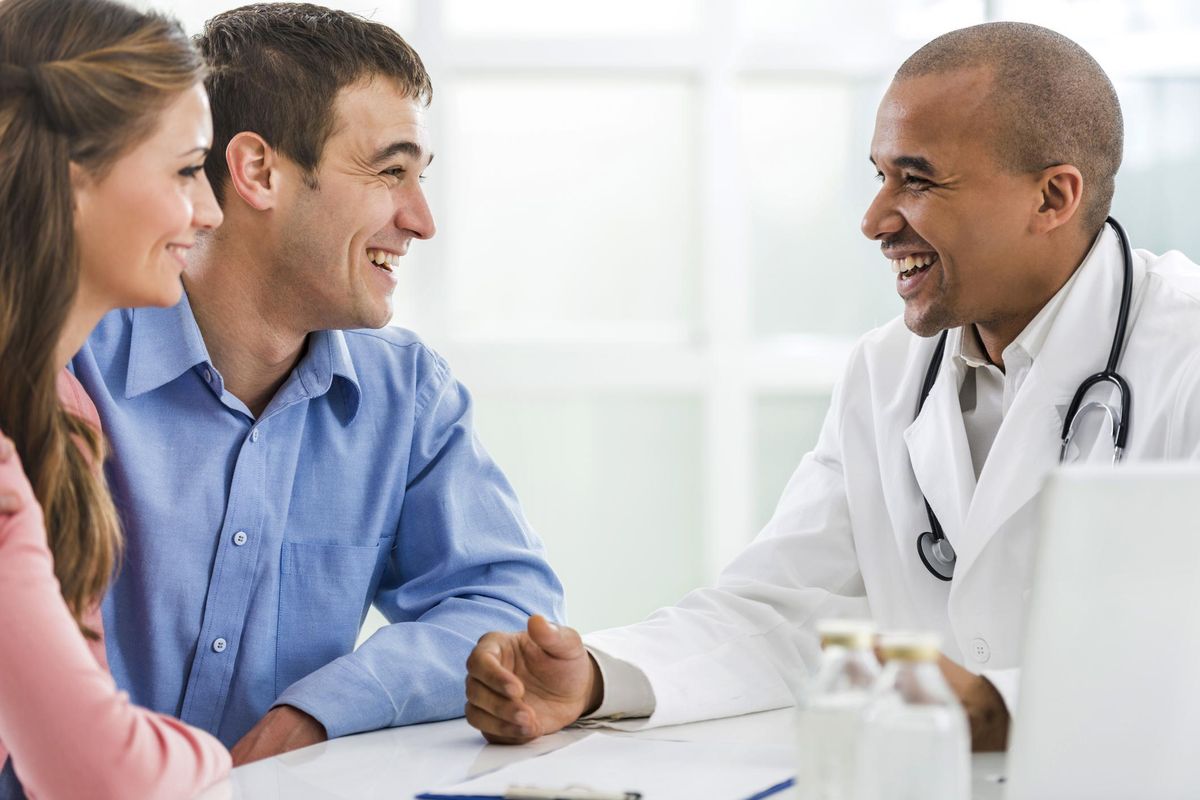 Happy couple talking to a doctor