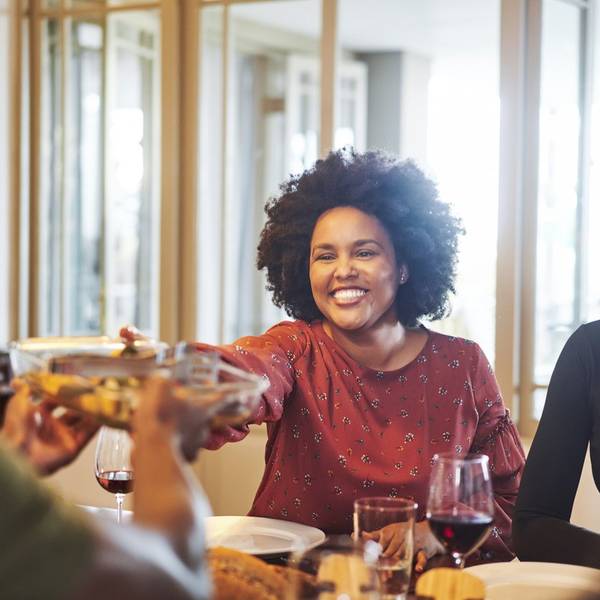 Happy friends sitting together at dining table