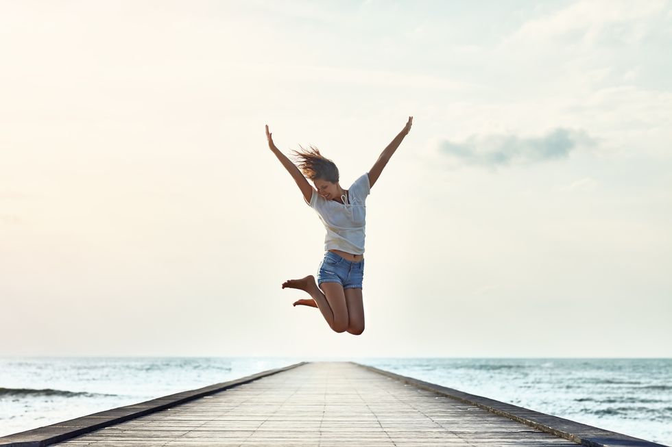Happy jumping girl on the pier