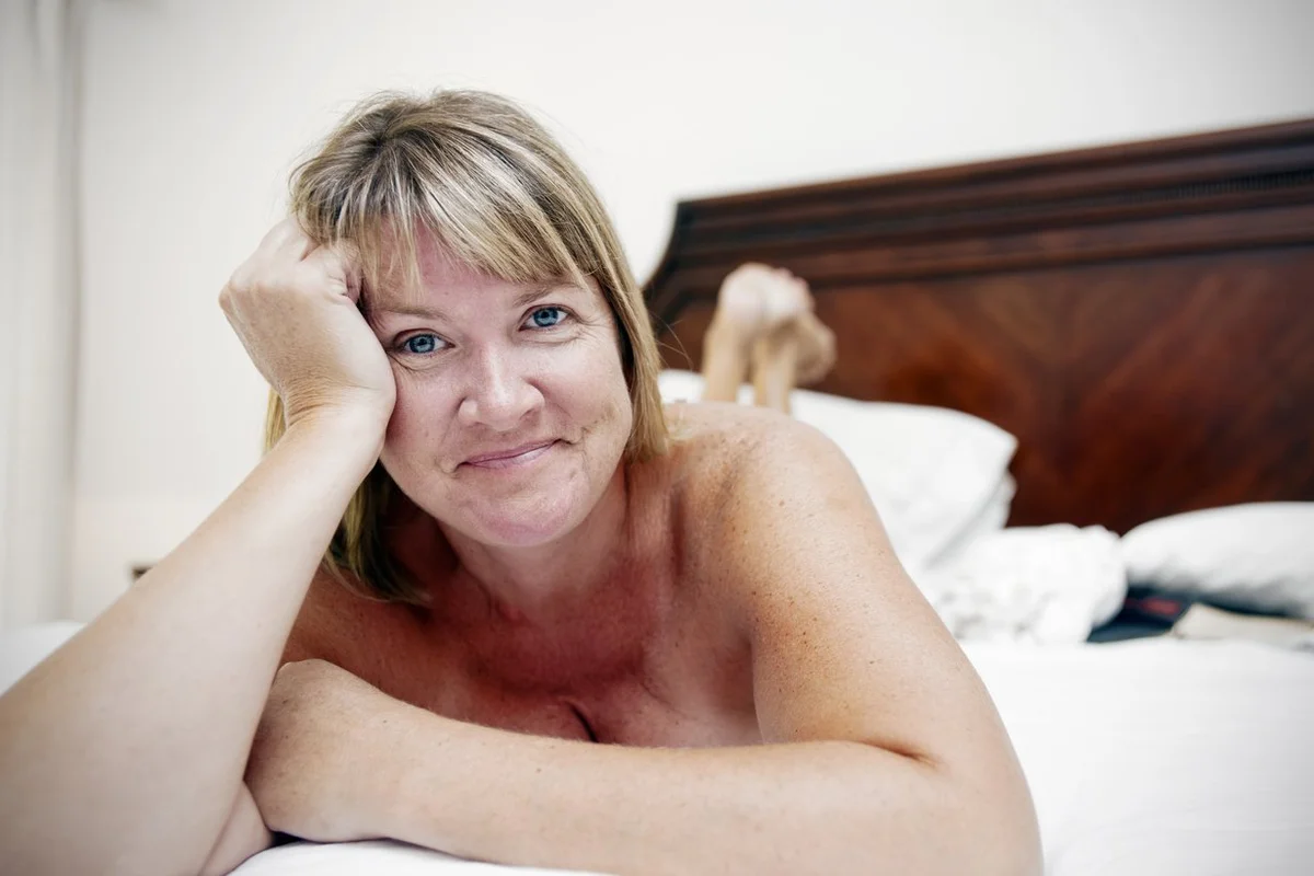 Happy, relaxed, Sexually Empowered middle-aged woman on a bed.