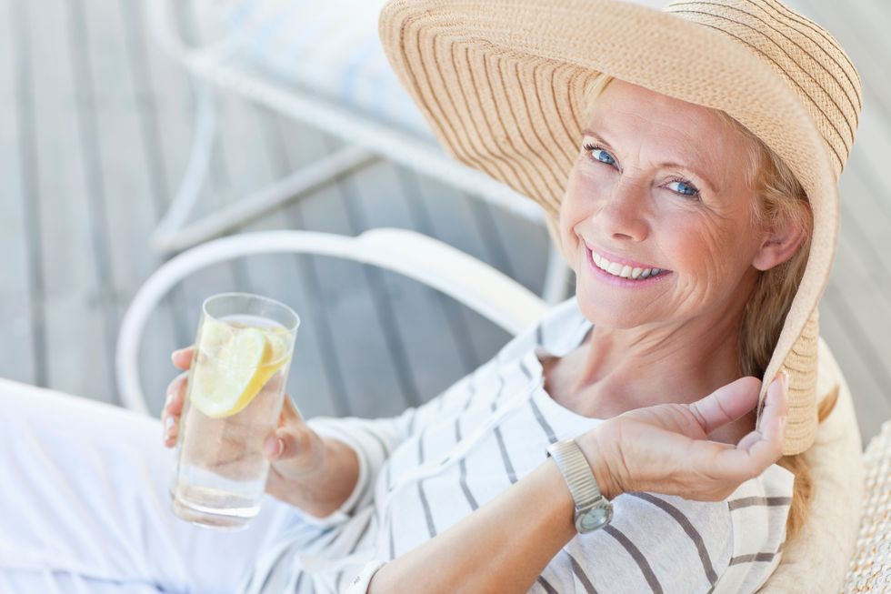 happy senior woman having a glass of lemonade outside