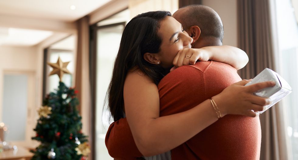 happy young couple exchanging Christmas gifts at home