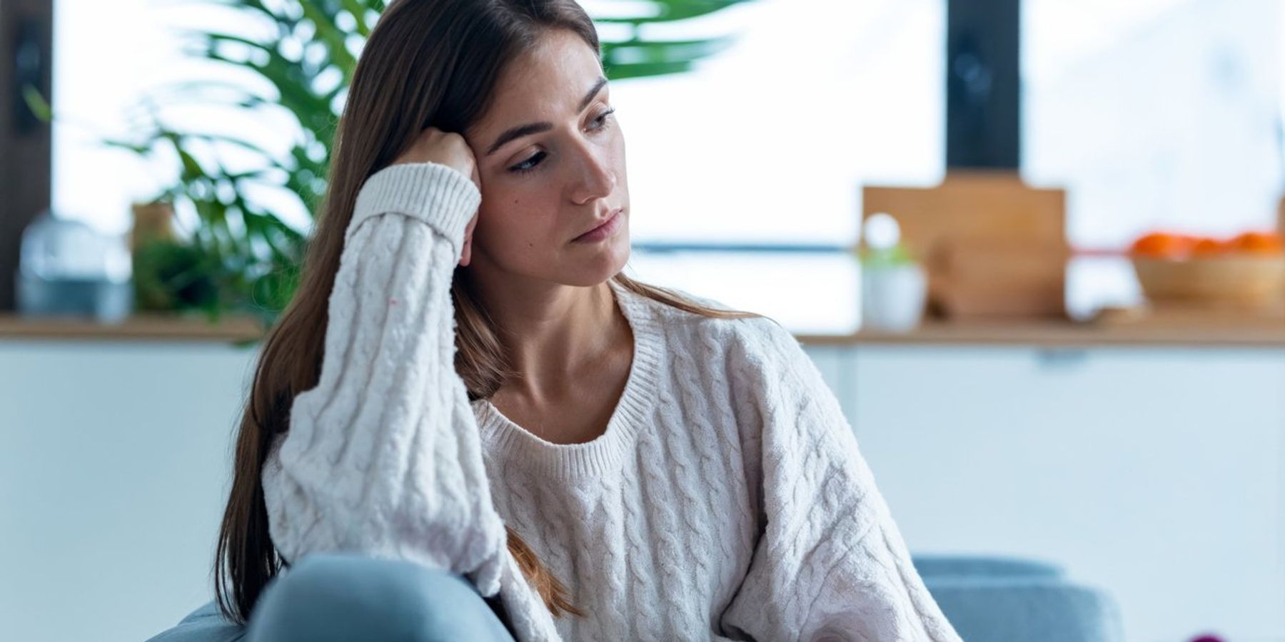 highly sensitive young woman thinking about her feelings while sitting on the sofa