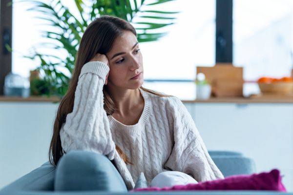 highly sensitive young woman thinking about her feelings while sitting on the sofa