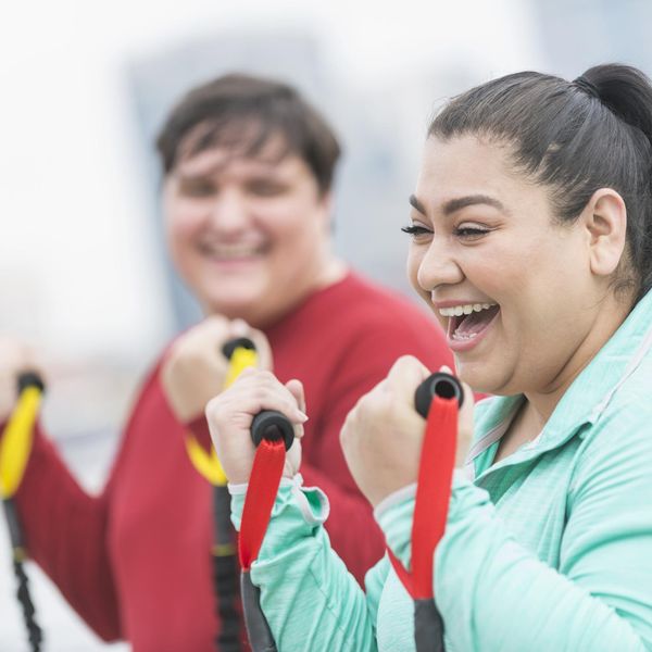 Hispanic woman, friend exercising with resistance bands