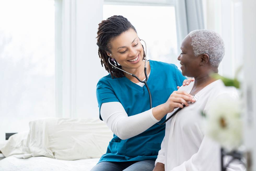 home healthcare nurse checks a senior female patient's vital signs.