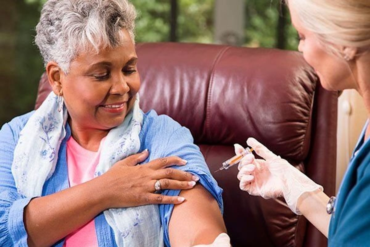 home healthcare nurse gives vaccine or medicine injection to senior adult patient at home