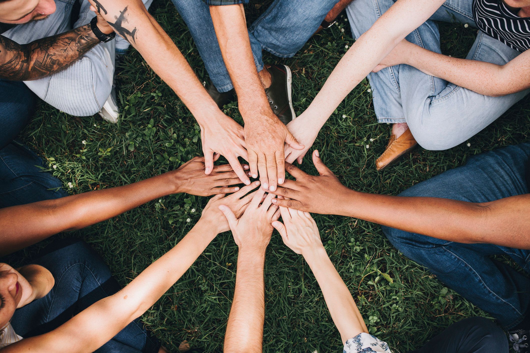 group of hands in the middle of a cirlce on the grass