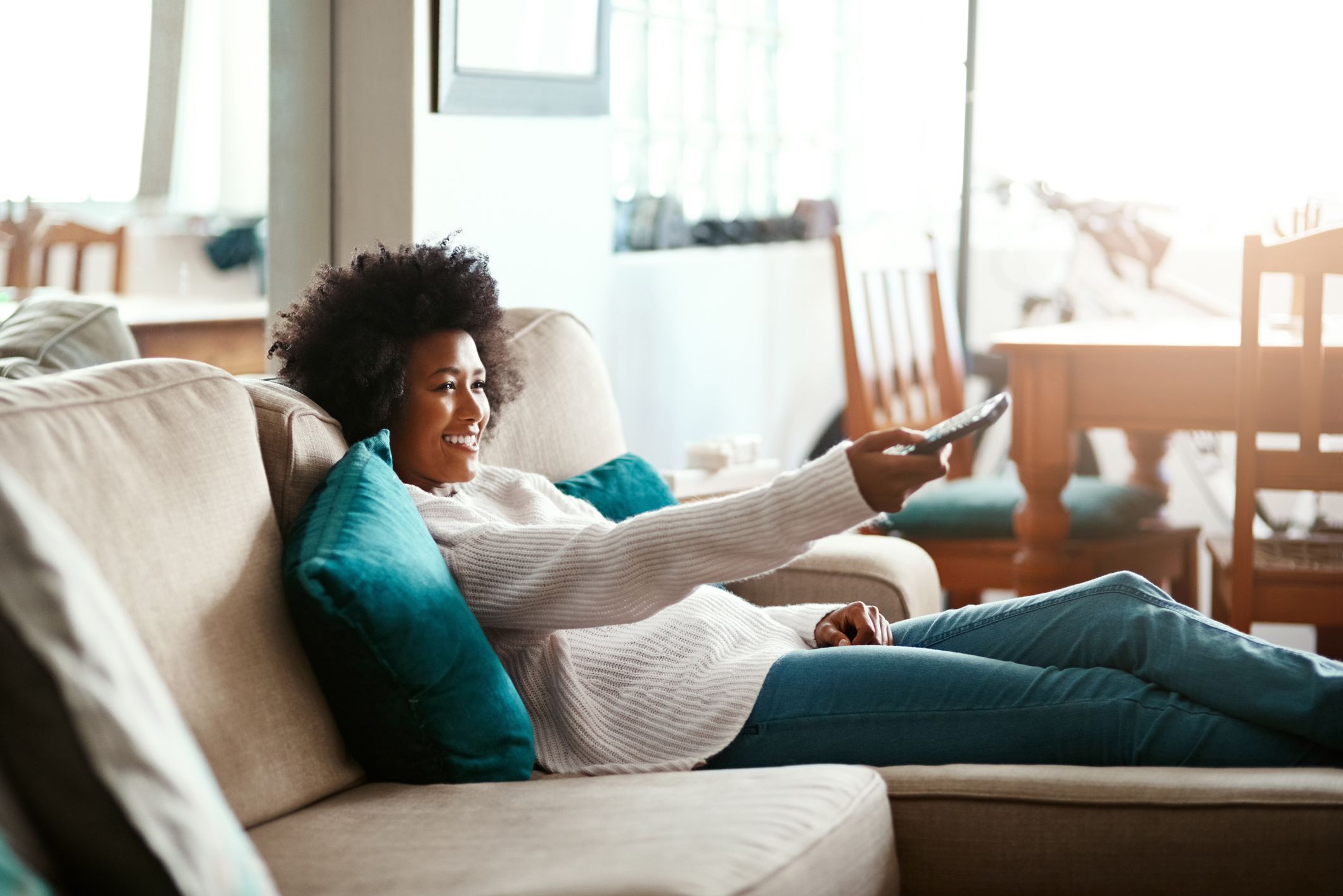 woman relaxing on the sofa at home and watching tv to Manage Stress