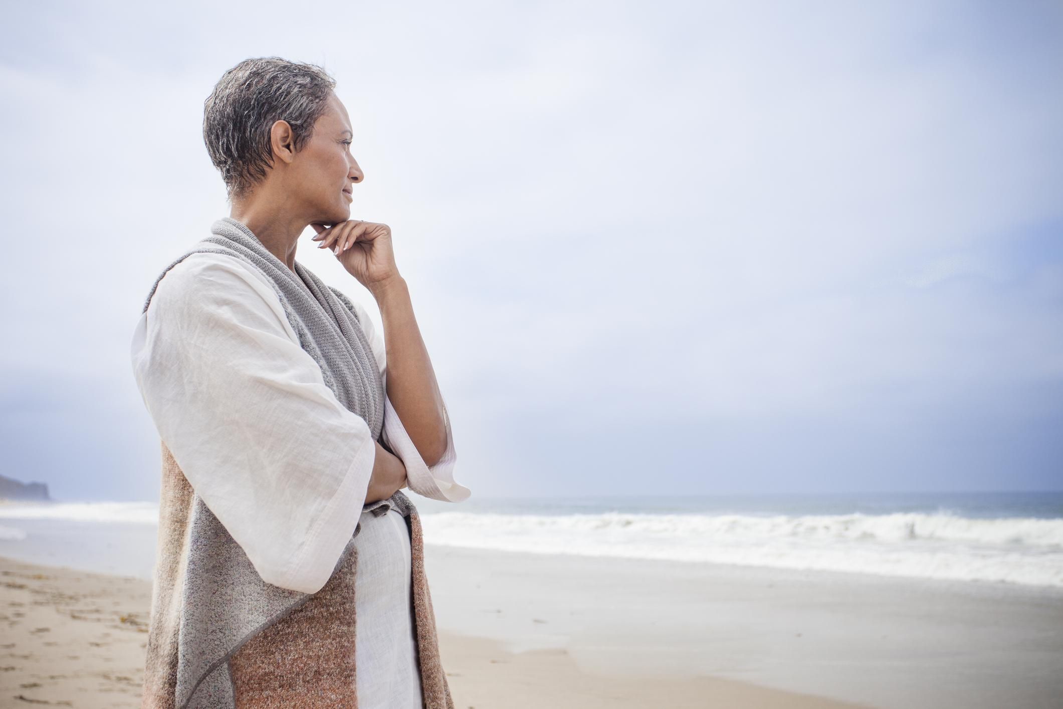 African American woman standing on the beach looking at at the ocean
