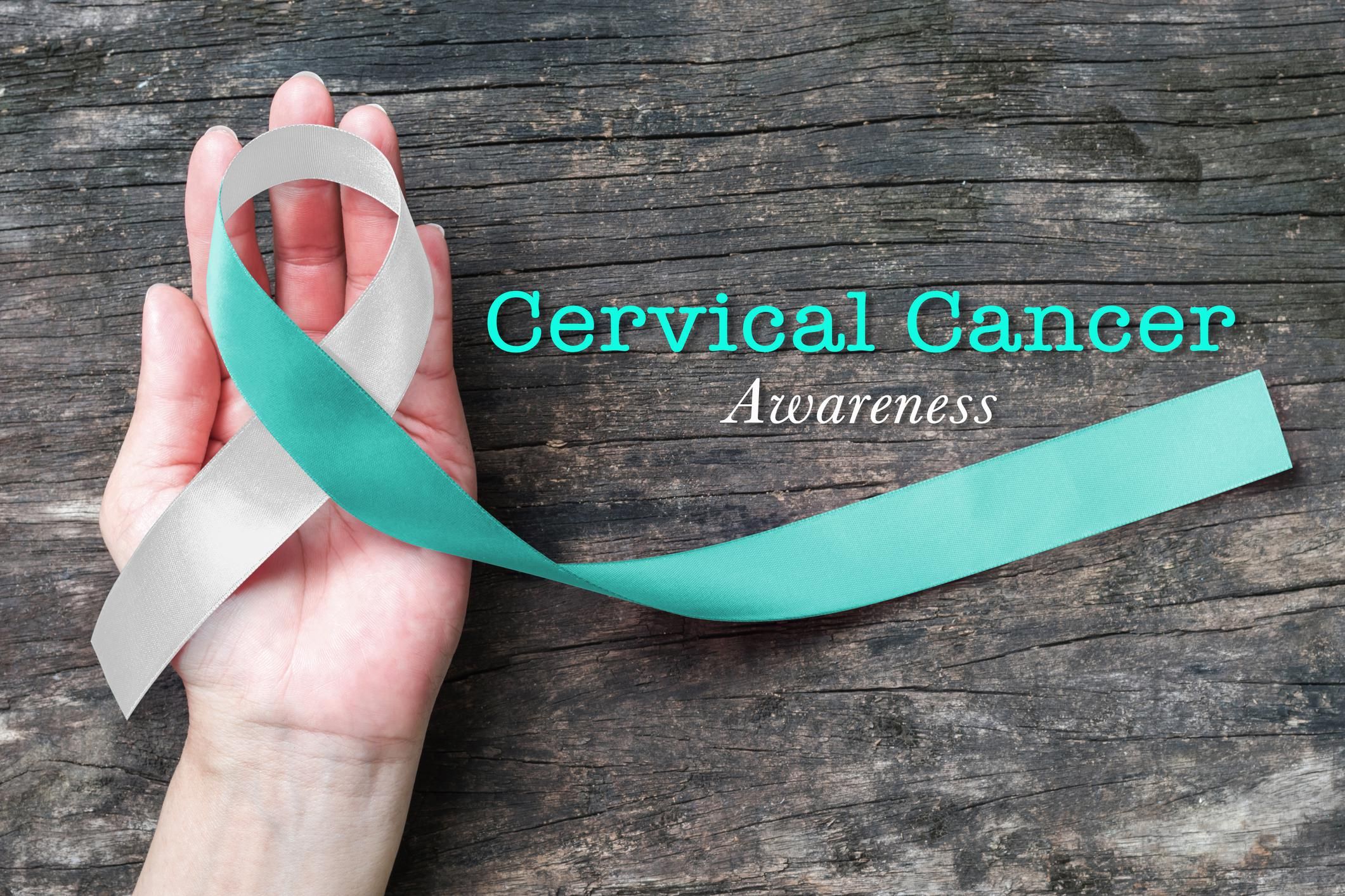 Cervical Cancer awareness with Teal and white ribbon symbolic bow color on woman helping hand support on old aged wood