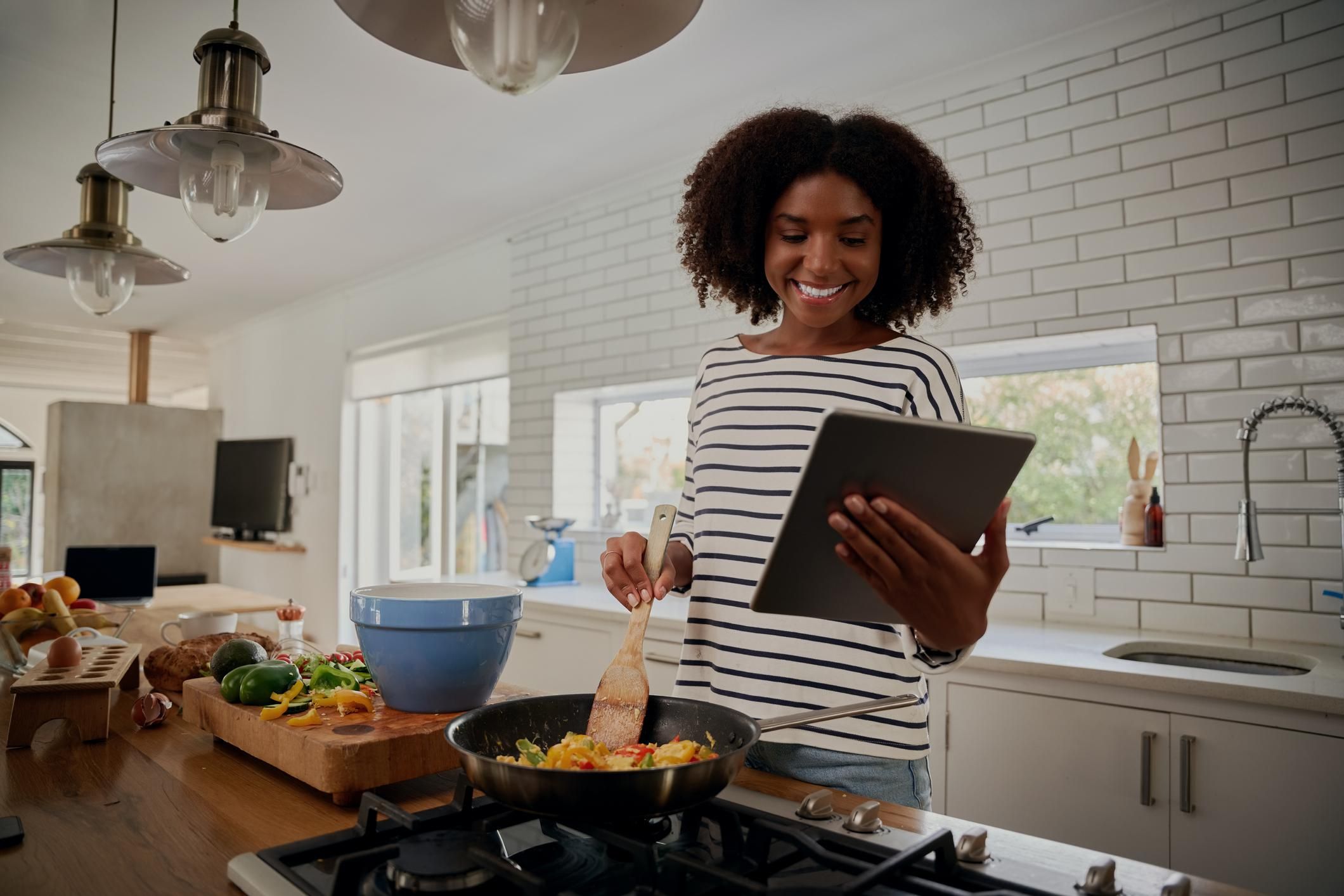 woman watching recipe in digital tablet while cooking