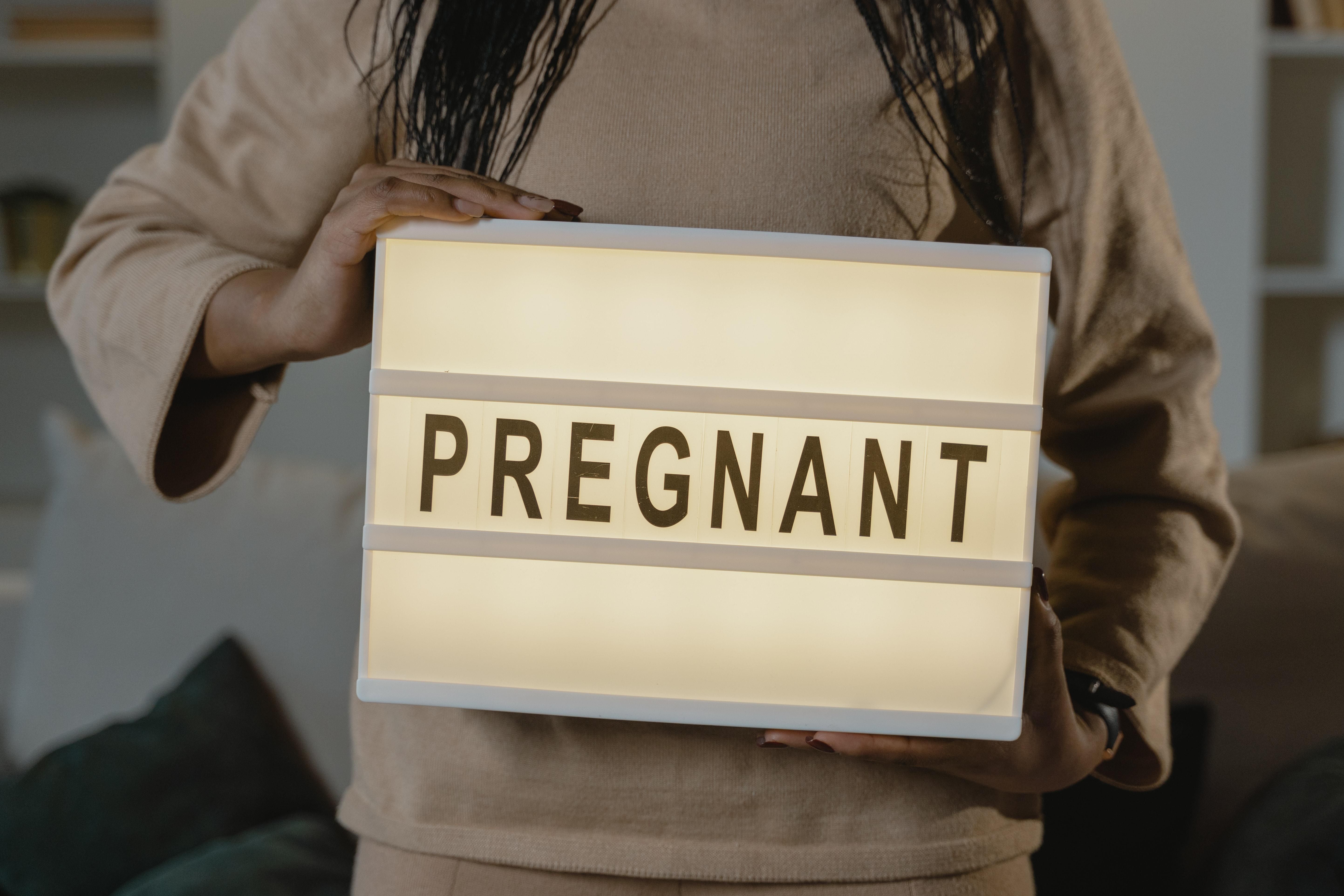 Woman Holding A Box With Pregnant Text
