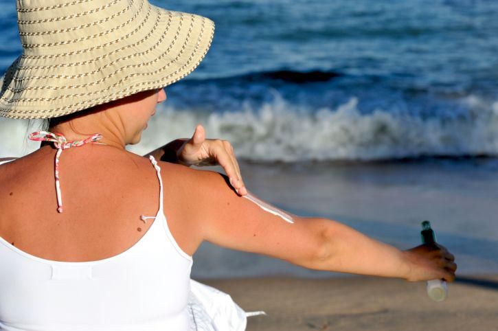 woman on the beach applying sunscreen