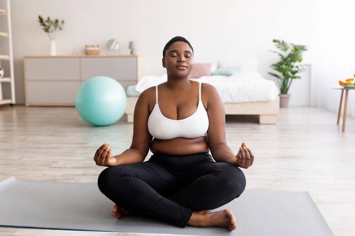 woman sitting in lotus pose, meditating with closed eyes