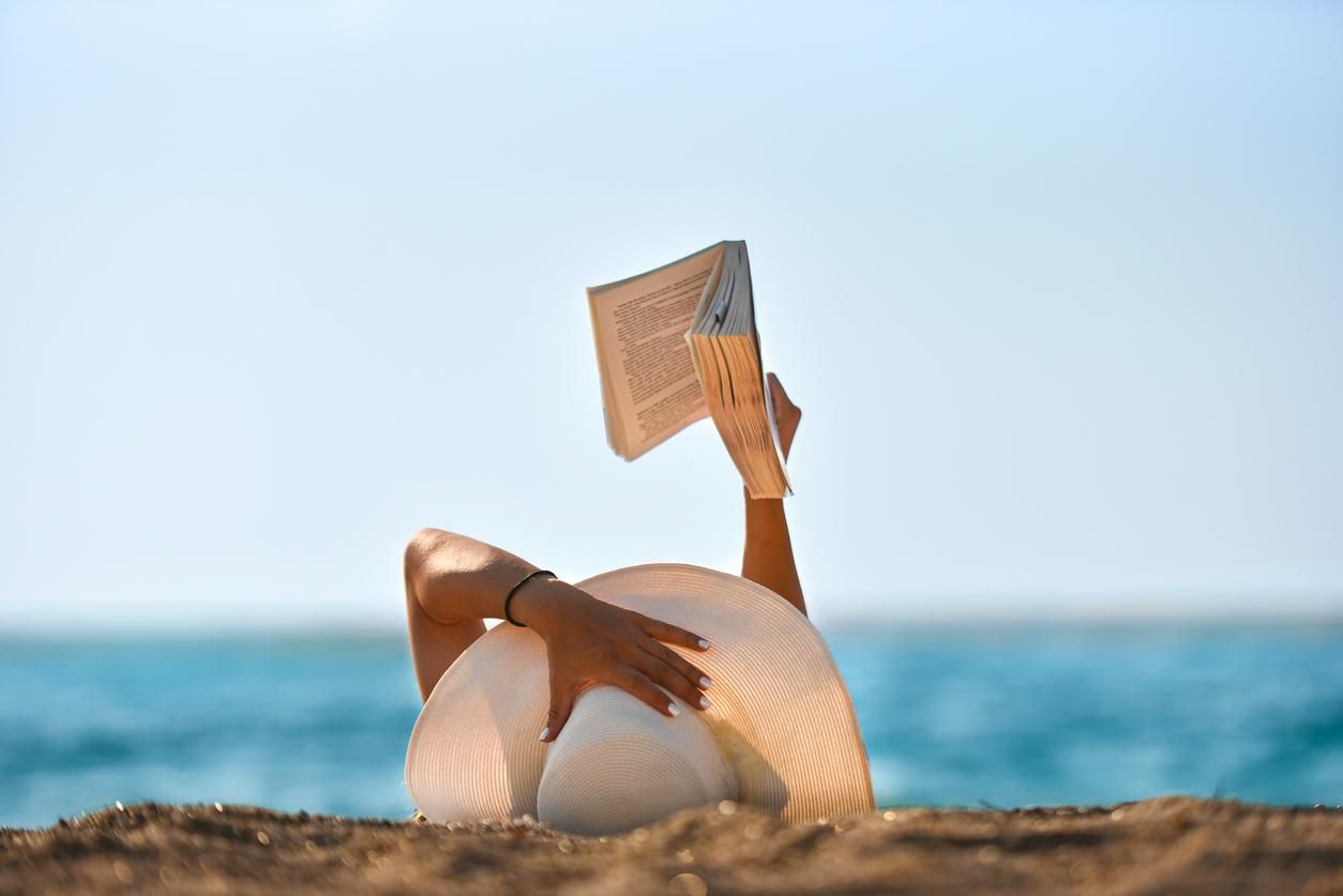 woman reads a book on the beach