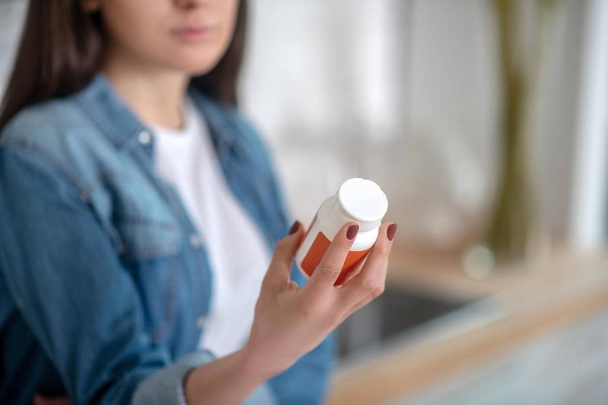 woman holding a container with pills