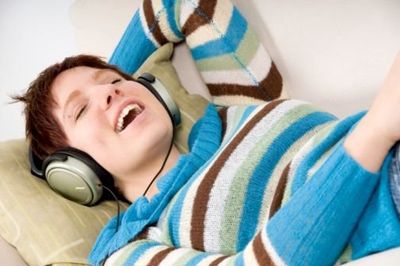 woman laying in her bed listening to music on headphones