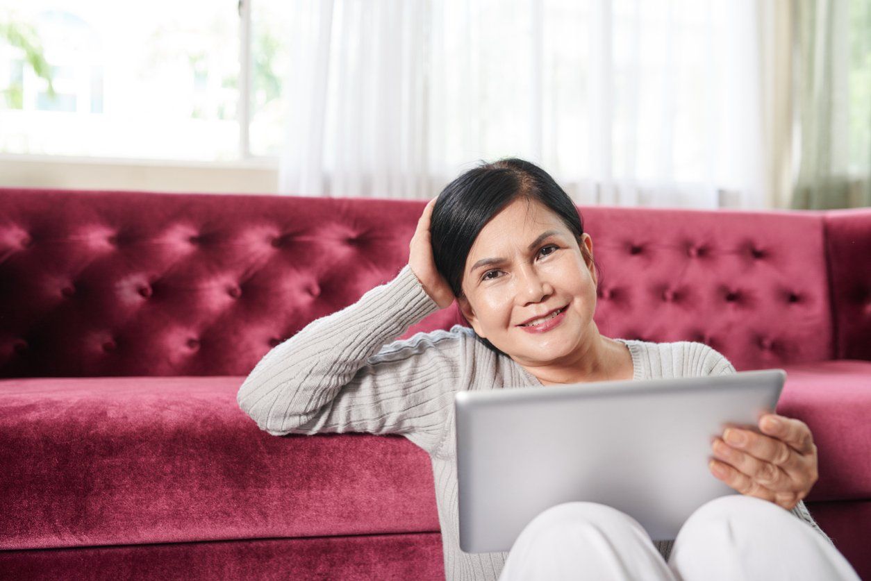 senior woman with tablet computer sitting on floor