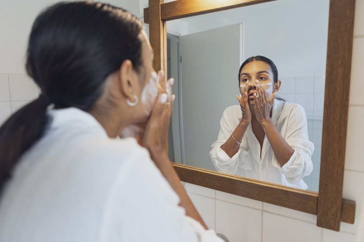 Woman washing face and looking in mirror