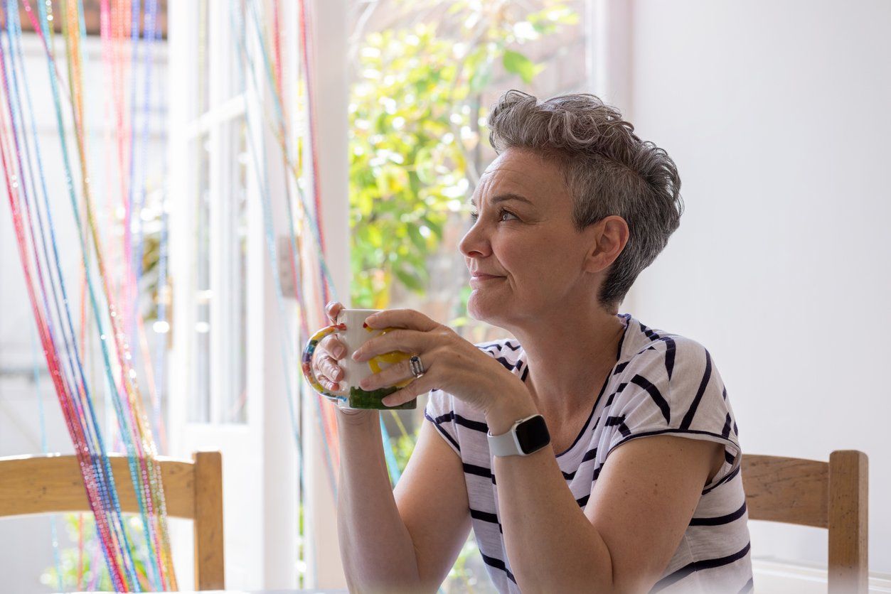 female sitting at a table in a kitchen, relaxing and having a cup of tea
