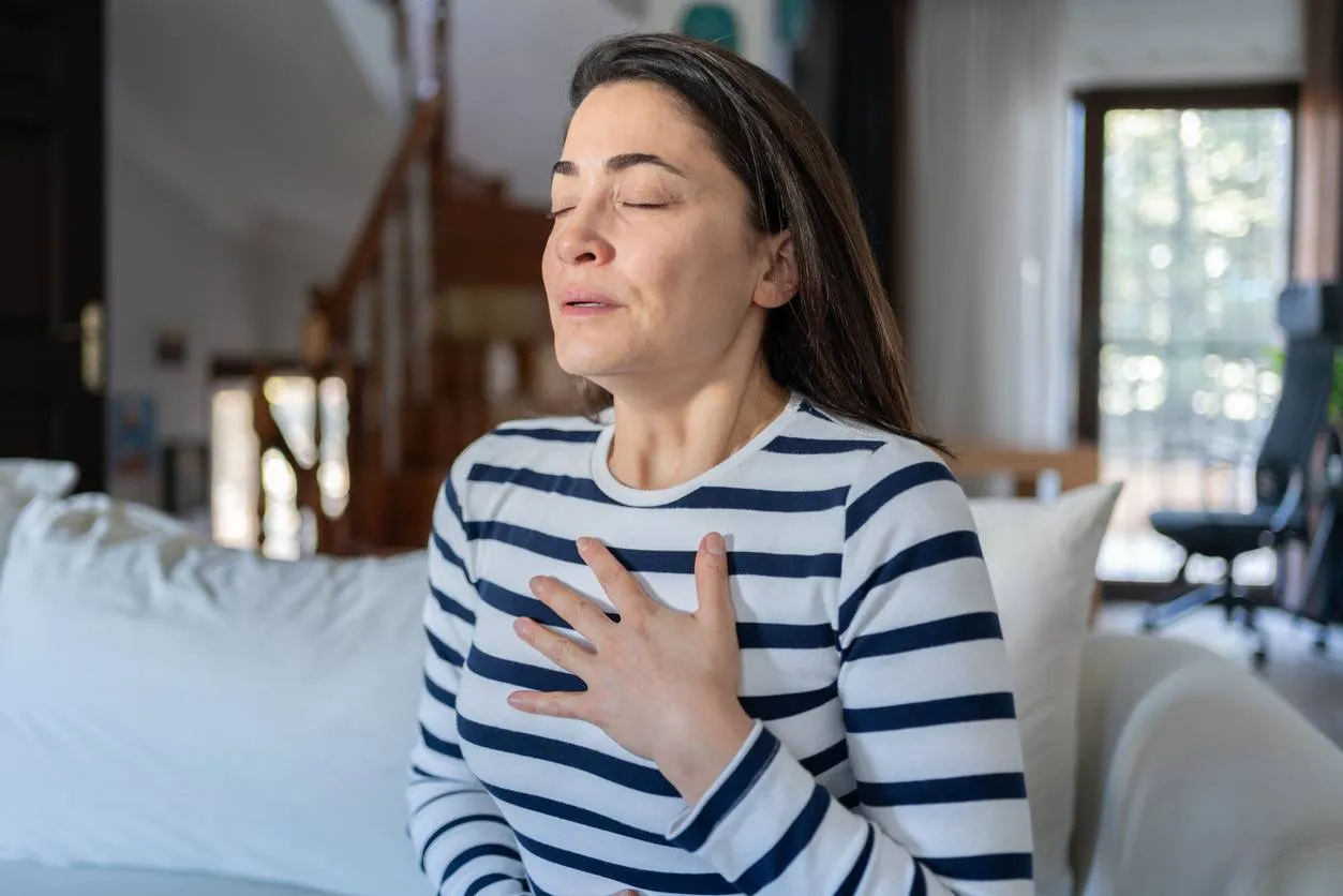 Woman With A Panic Attack Having Trouble Breathing Sitting On Sofa At Home