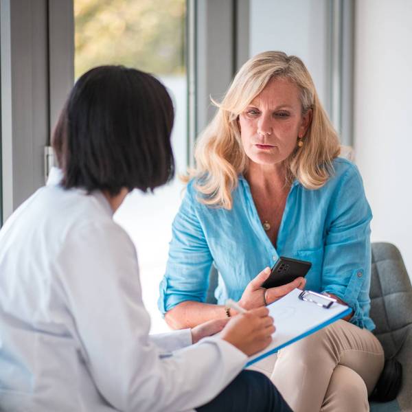 In a doctor's office with a mature Caucasian female patient and an Asian female doctor.
