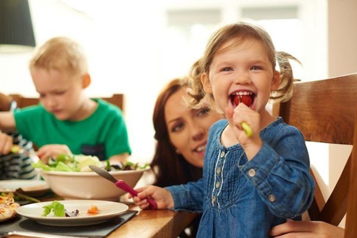 little girl eating dinner with her family