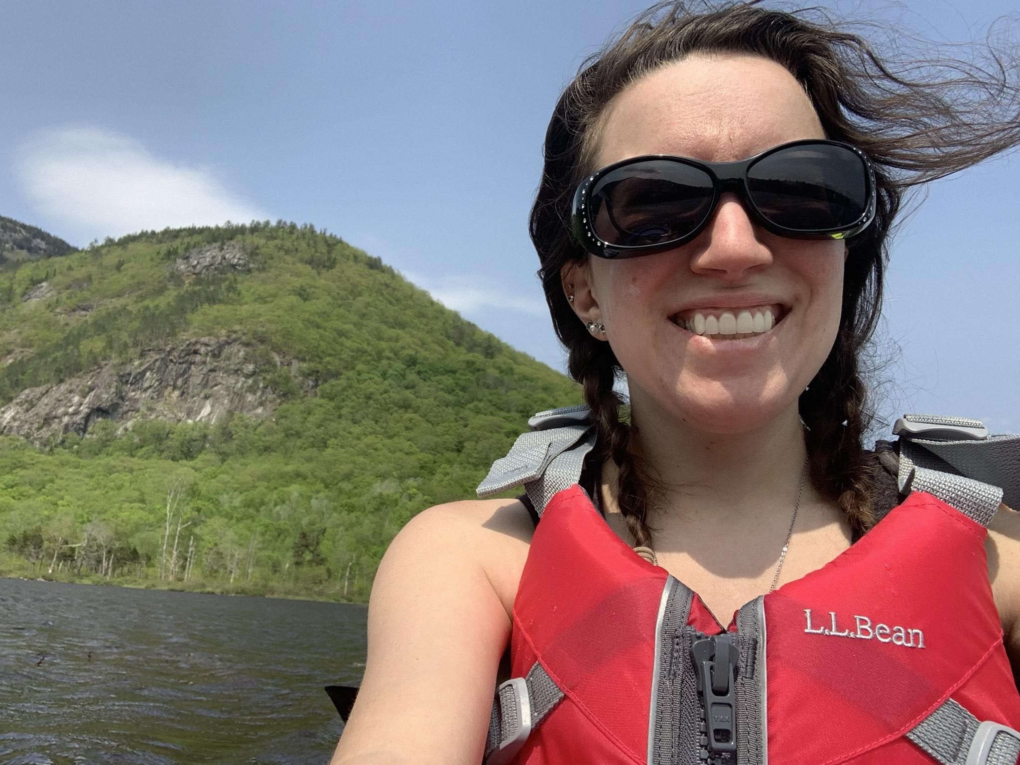 LIz kayaking in front of a mountain wearing a red life vest