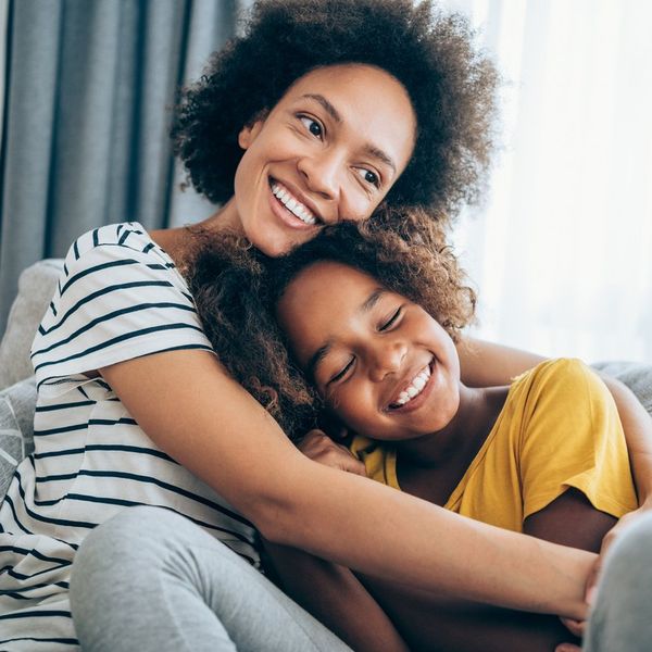 Lovely mother embracing her cute daughter on the sofa at home.