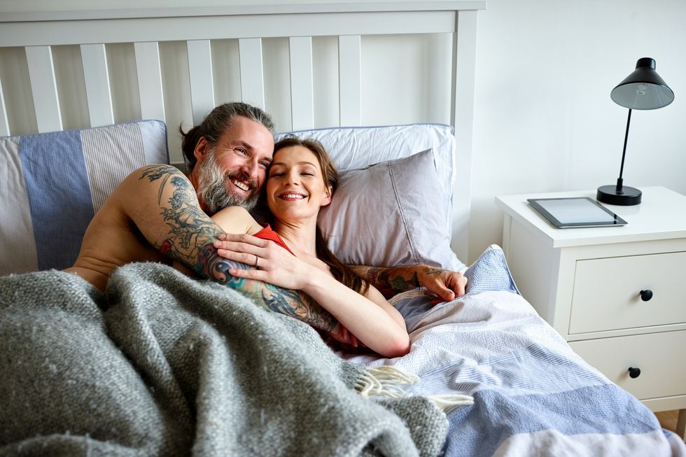 Loving couple lying together and embracing on bed at home