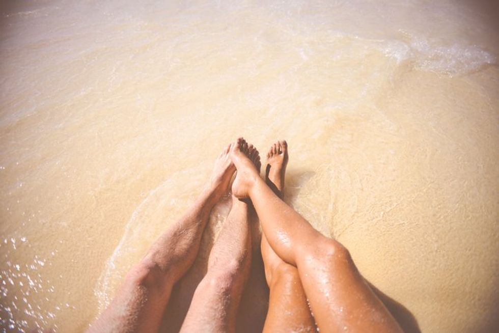 Low Section Of Man And Woman Relaxing On Beach