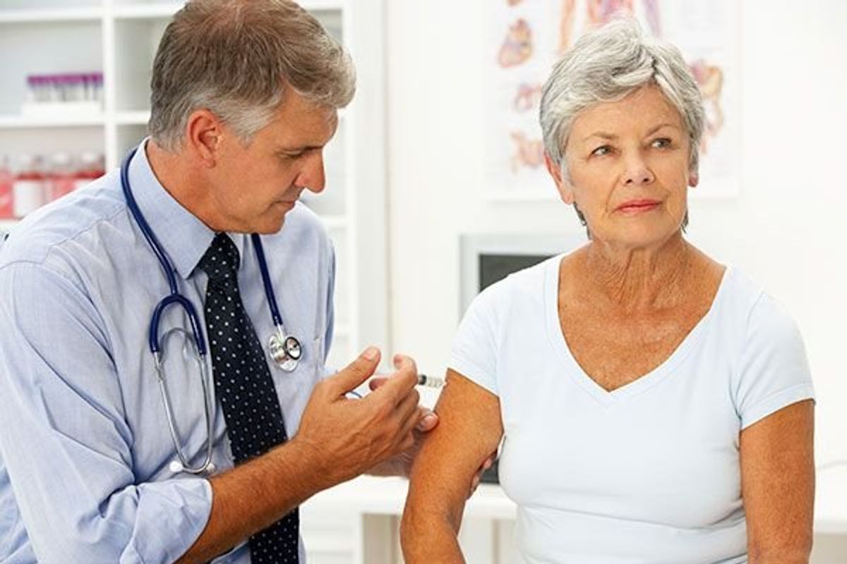 male doctor injecting a senior female patient