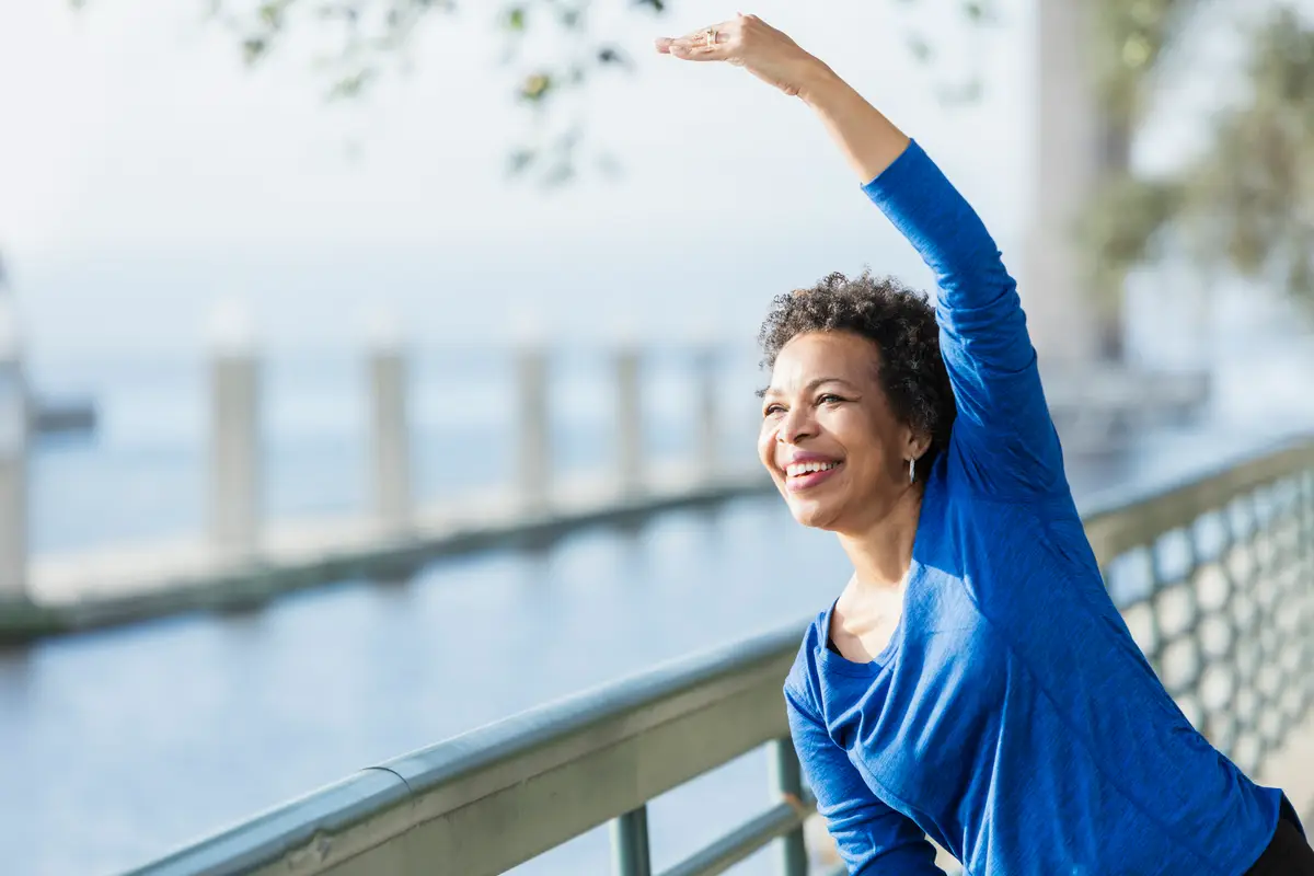mature African-American woman in her 50s wearing sport clothing, exercising on a city waterfront