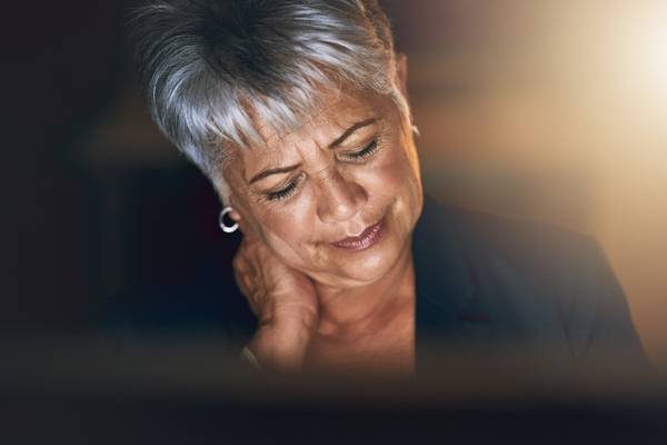 mature businesswoman experiencing strain during a late night at work