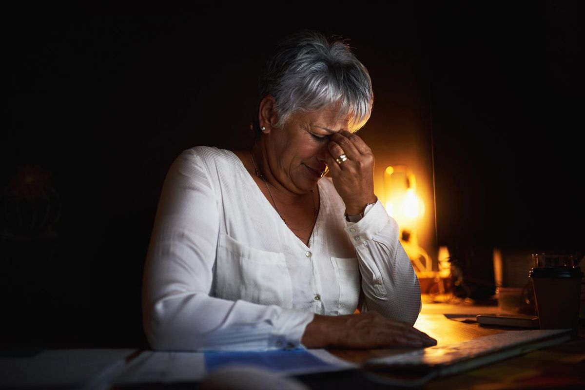 mature businesswoman looking stressed out while working late in an office