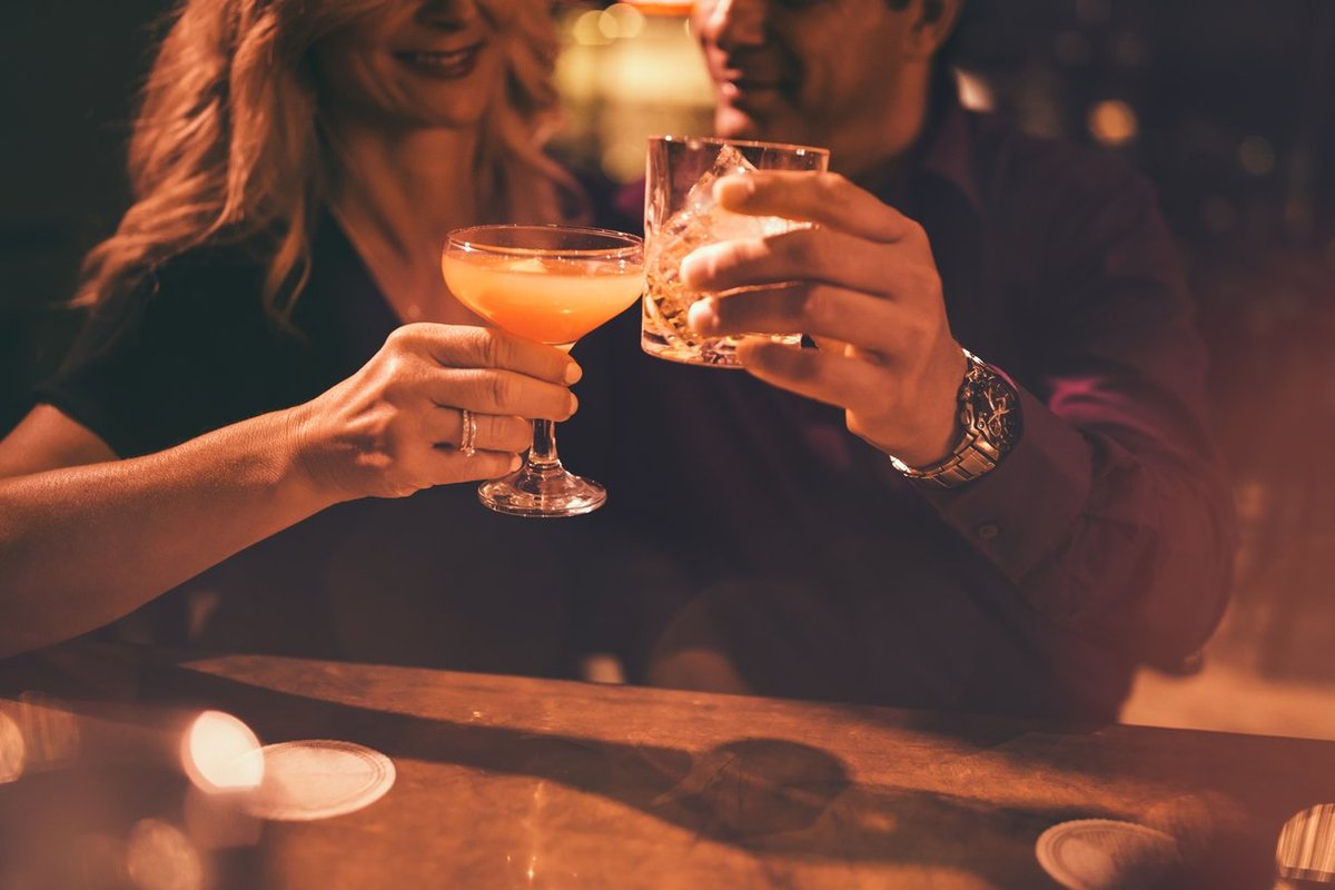 mature couple toasting with drinks at bar