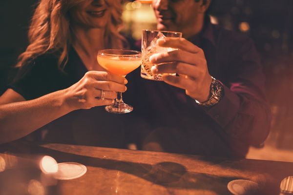mature couple toasting with drinks at bar