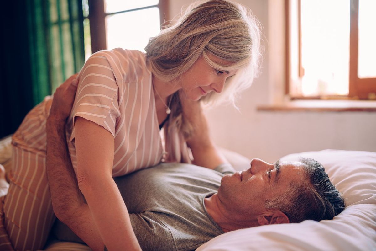 Mature husband and wife flirting while lying down in bed