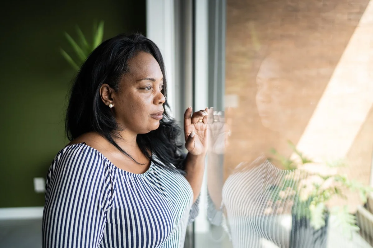 Mature woman contemplating at home, looking out the window