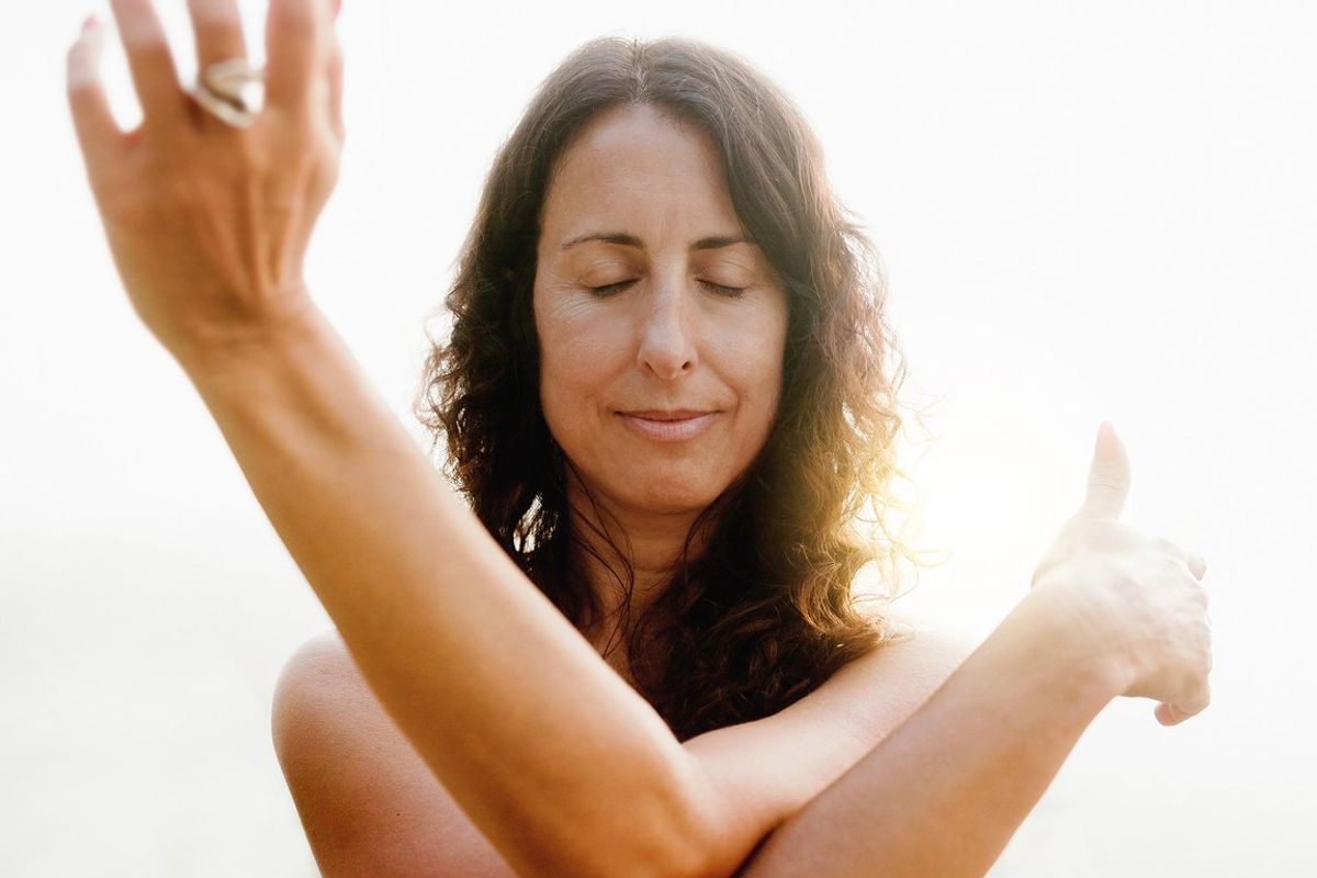 Mature woman doing flow meditation exercise outdoors with sunset background