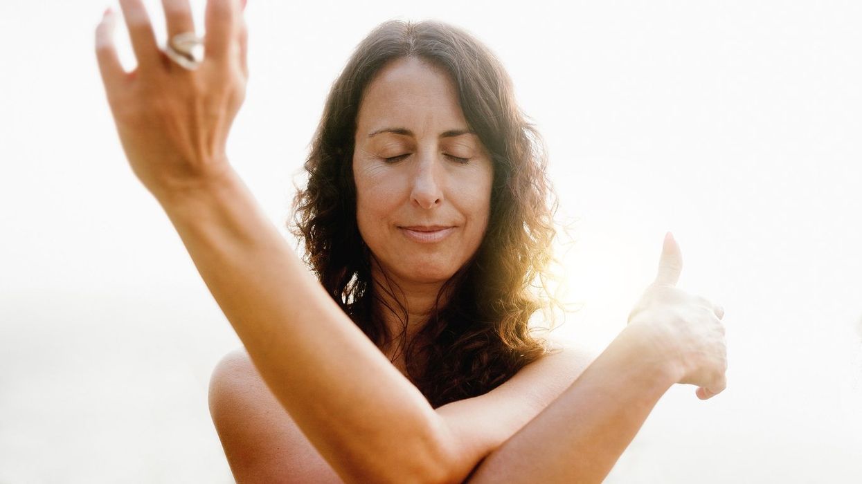Mature woman doing flow meditation exercise outdoors with sunset background