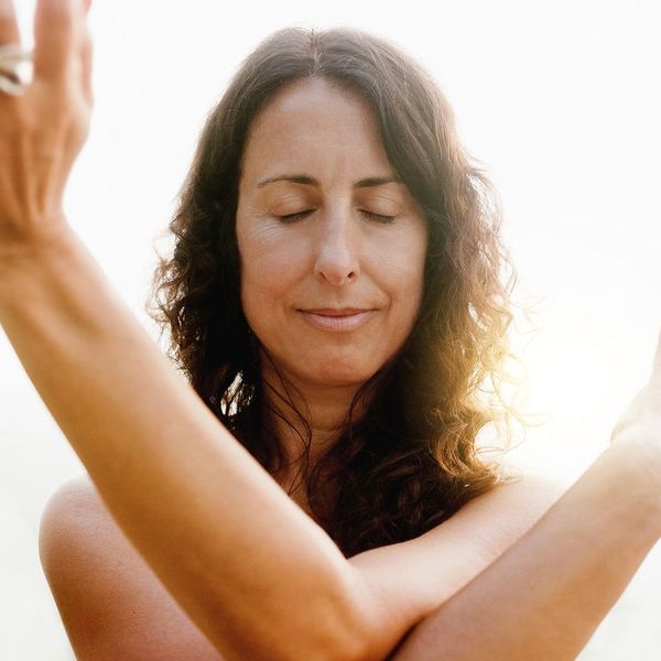 Mature woman doing flow meditation exercise outdoors with sunset background