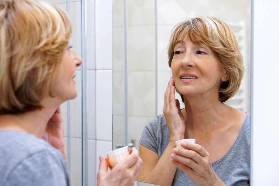 Mature woman examining her face in the mirror