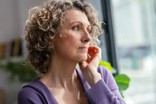 mature woman looking forwards near the window