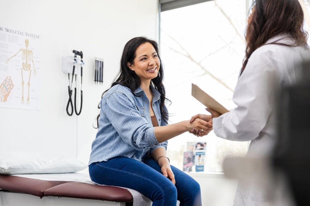 Mid adult female patient shakes hands with her doctor during annual checkup